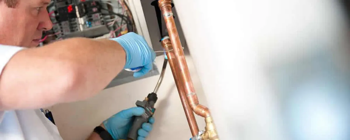 Water heater repair technician testing copper pipe connections and controls in Austin, TX